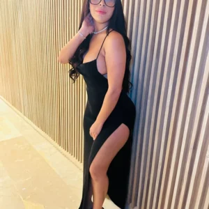 Chica de compañía con vestido negro apoyada en la pared